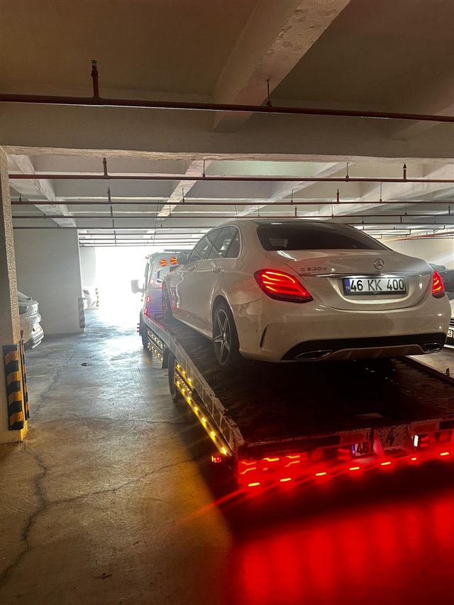 Kapalı otoparkta çekiciye yüklenmiş beyaz sedan